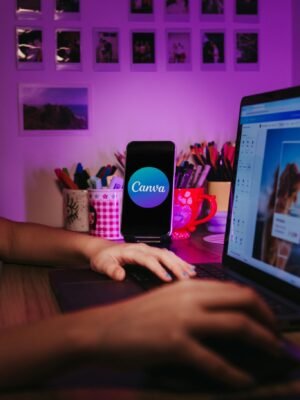 A creative home workspace with a laptop and smartphone displaying Canva, showcasing a vibrant, organized desk setup.